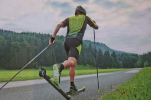Skater in Sportkleidung beim Skirollerfahren in einer grünen Landschaft.