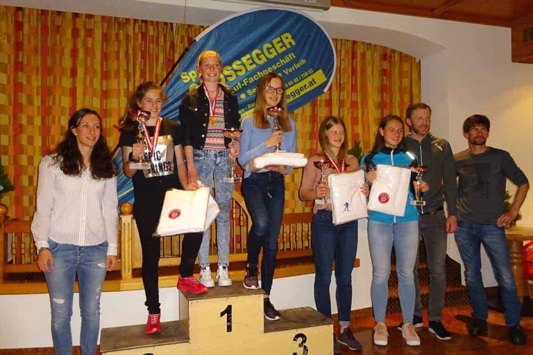 Jugendliche Langläuferinnen und -läufer auf dem Siegertreppchen bei Sport Großegger in Saalfelden.