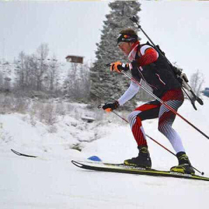 Langläufer in Aktion, Technik Skating, Schnee und winterliche Landschaft im Hintergrund.