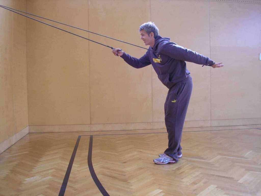 Mann trainiert mit einem Expander, um Langlauftechnik zu verbessern. Fitnessraum in Saalfelden.